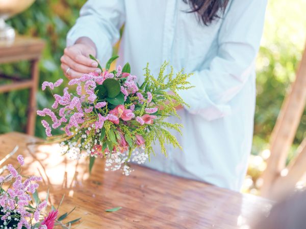 Crop florist with bunch of flowers in garden
