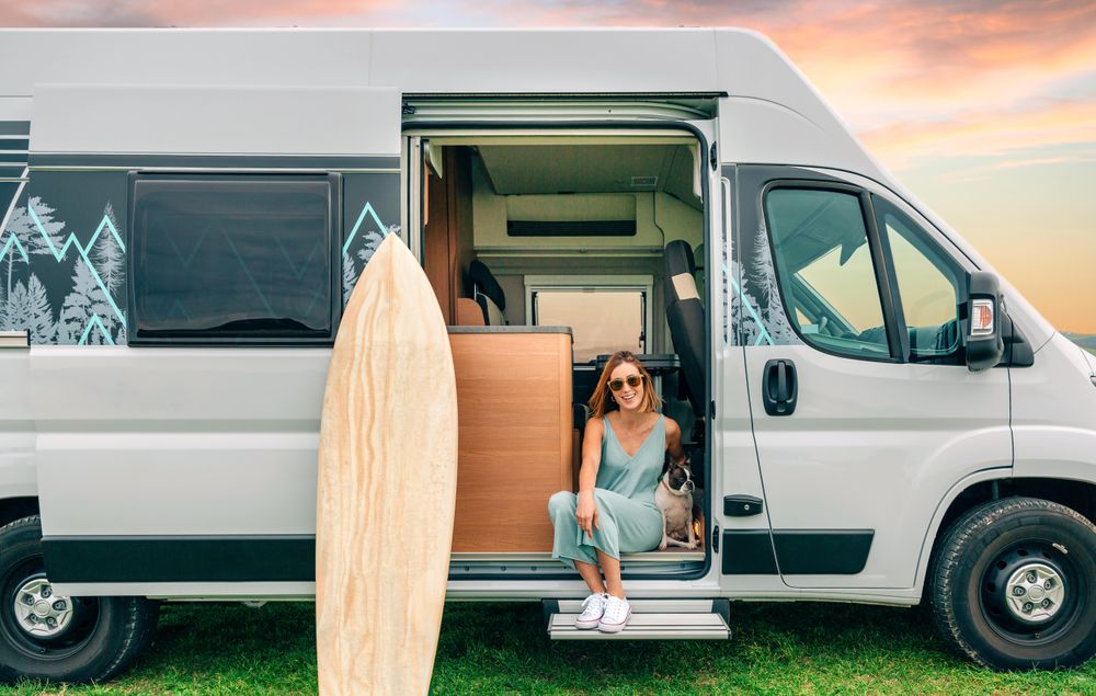 Smiling woman sitting on stoop of motorhome door with cute dog