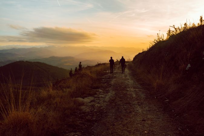 Men hugging near dog on road on hill
