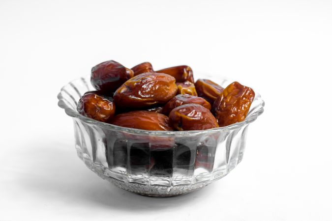 Dates fruits in a bowl glass on isolated plain background