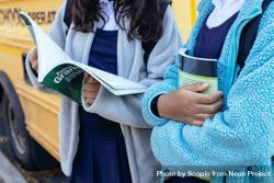 Close-up shot of two girls in school uniforms holding school books standing outdoor 49pMB5