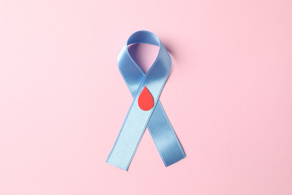 Diabetes. Blue awareness ribbon with decorated blood drop on pink background