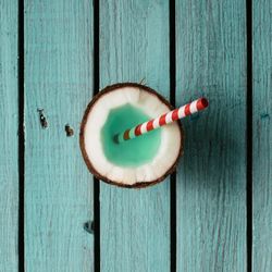 Coconut drink with straw on blue wooden background