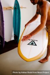Man preparing surfboard at home before heading to the beach 0gJ93b
