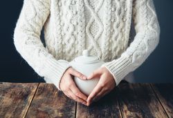 Woman holding tea pot on wooden table