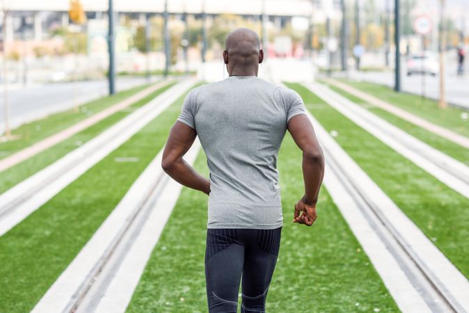 Close of rear view of male in athletic wear sprinting outside