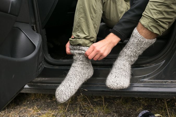 Man changing socks after camping in car
