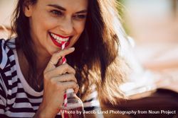 Close up of smiling female drinking soft drink on a summer day 0Wdpr5