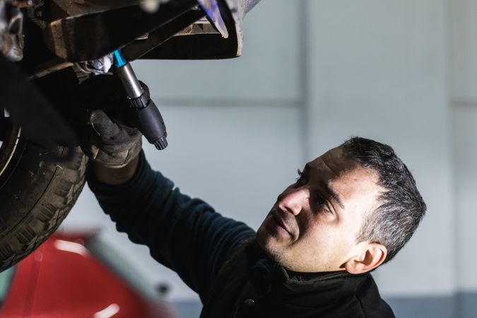 Repairman removing car details with torch during work in auto service