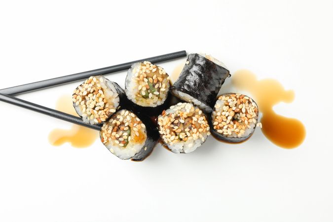 Delicious sushi rolls, soy and chopsticks on plain background, top view