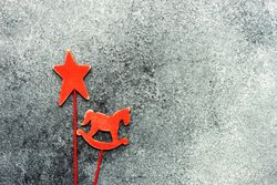 Two red wooden ornaments on grey background