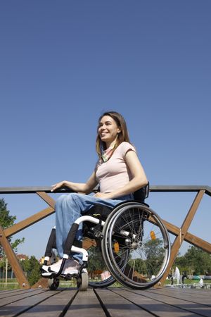 Happy woman in a wheelchair on a bridge, vertical