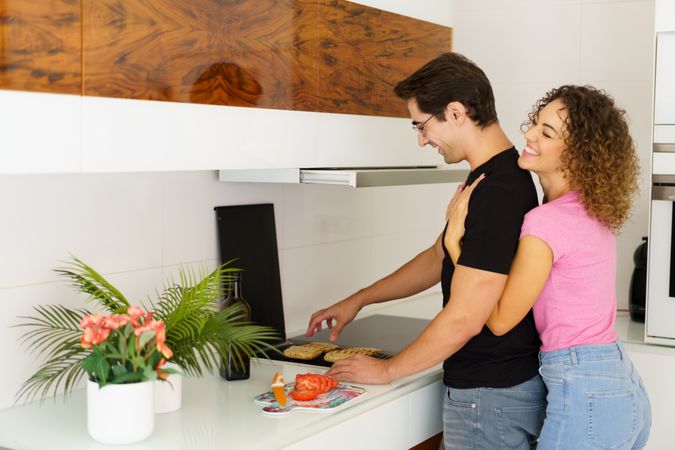 Affectionate couple making breakfast together in bright kitchen