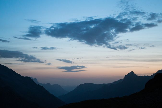 Dark mountain range under cloudy sky in twilight