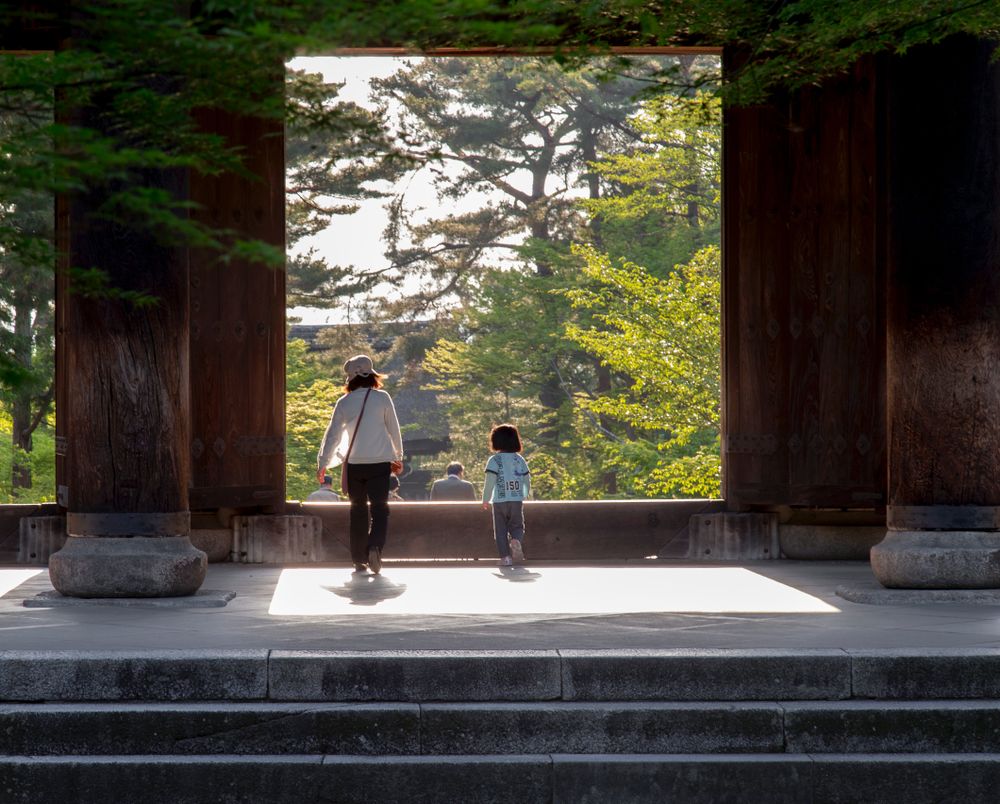 Back view of happy mother and child standing in concrete gazebo