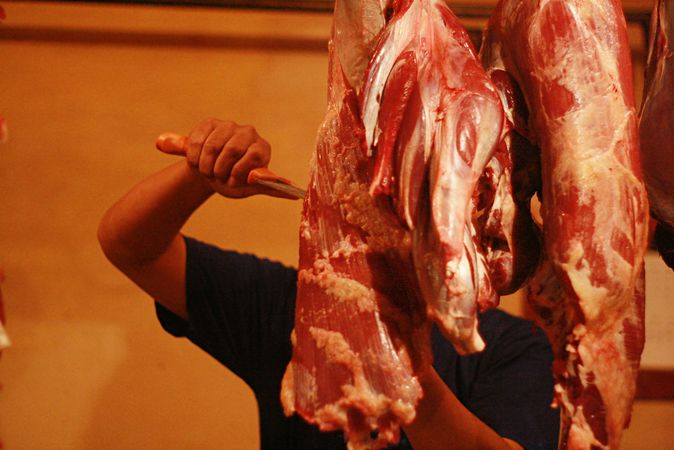 Man cutting meat in butchers shop