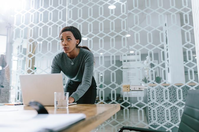 Young businesswoman working on laptop and looking away