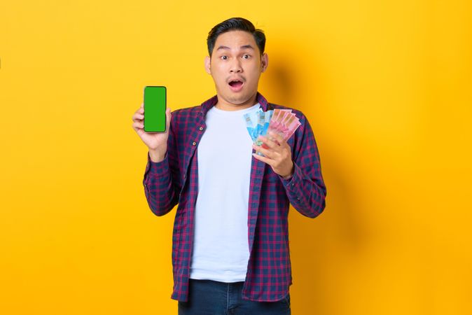 Surprised man with smart phone mock up and cash