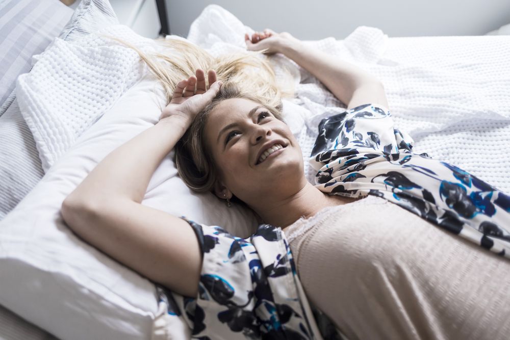 Portrait of a happy, relaxed adult woman lying on a bed