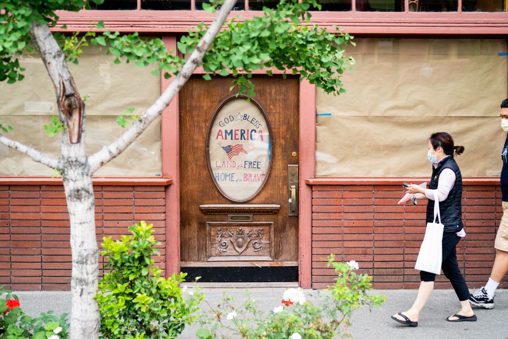 People walking on sidewalk in front of closed business