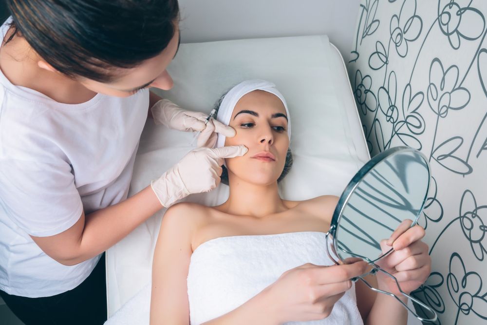 Female checking face in mirror after botox in a beauty salon
