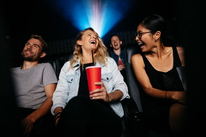 Young woman with friends in cinema hall watching movie