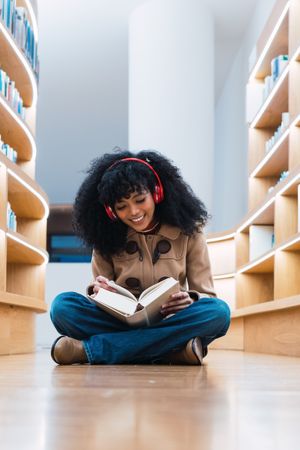Glad Black female reading book in library