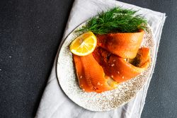 Raw herring fish on plate served with dill and lemon with copy space