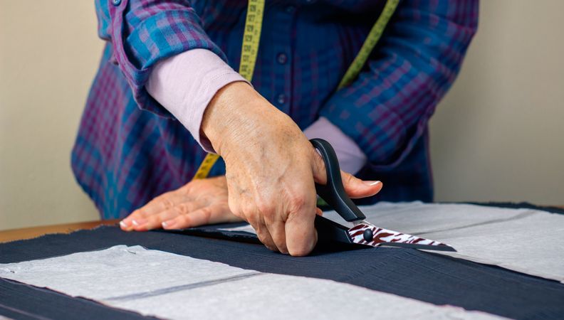 Hands of dressmaker cutting a cloth