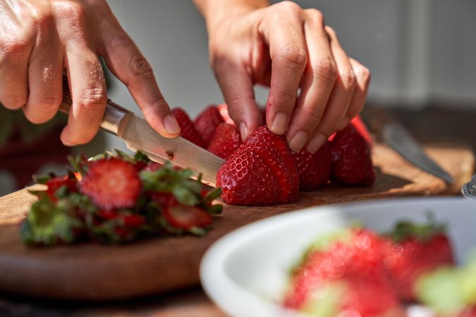 Crop cook cutting strawberry with knife