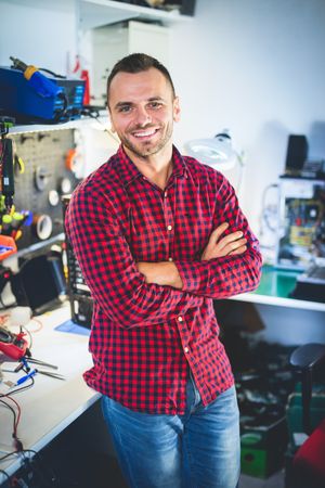 Smiling repairman standing at workplace
