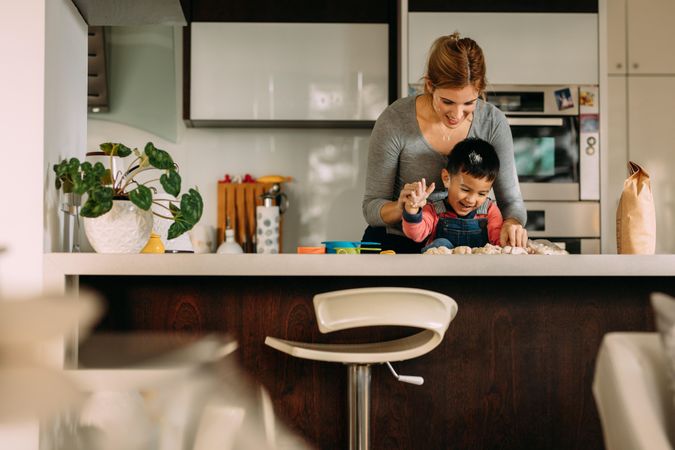 Happy young woman and child making cookies in kitchen
