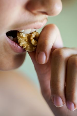 Side view close up of teenage girl eating healthy walnut