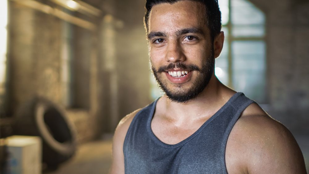 Sweaty Muscular Man Smiles on Camera.