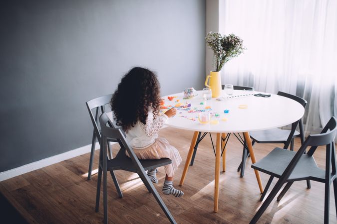 Little girl sitting at a round table crafting