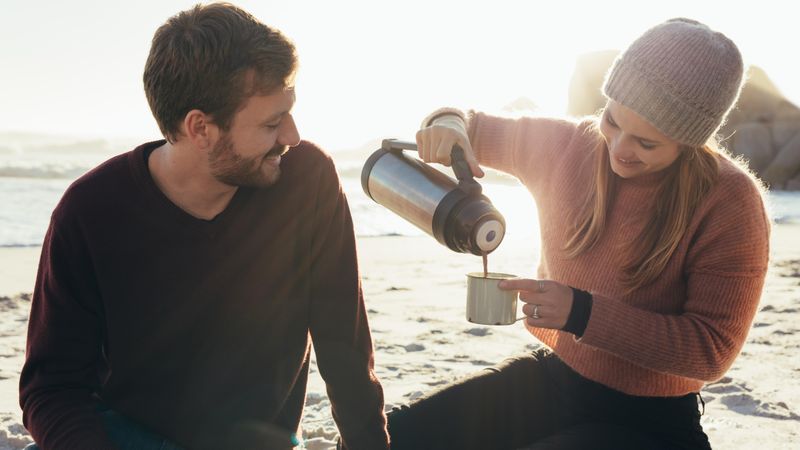 Beautiful young couple having coffee at the beach