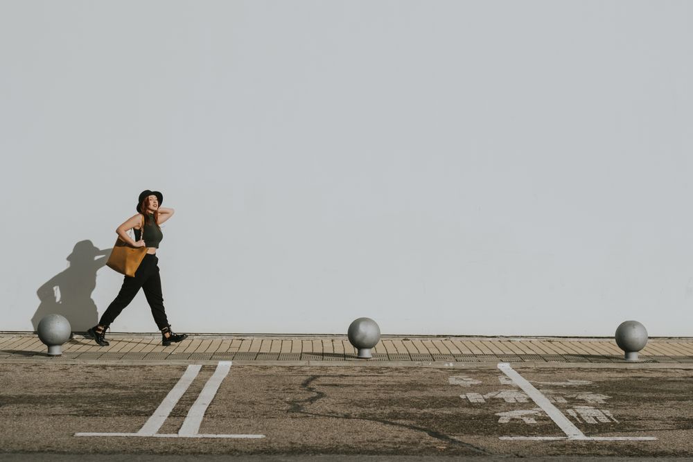 Woman with bag walking along parking lot