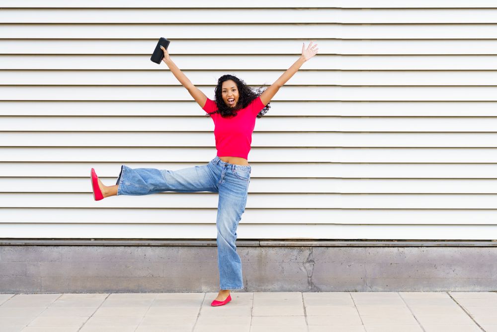A Joyful Young Woman Celebrating Excitedly Outdoors While Wearing a Stylish and Trendy Outfit