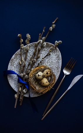 Top view of blue table and bird's nest on grey table with pussy willow for Easter table setting