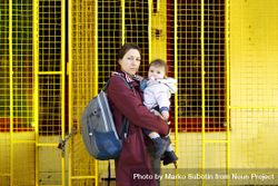 Side view of a woman standing with her child in front of yellow wall 4My9r4