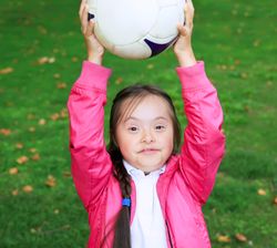 Young girl playing in a public park with a soccer ball on her head