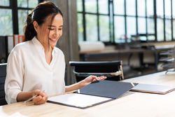 Smiling woman reading through report at work