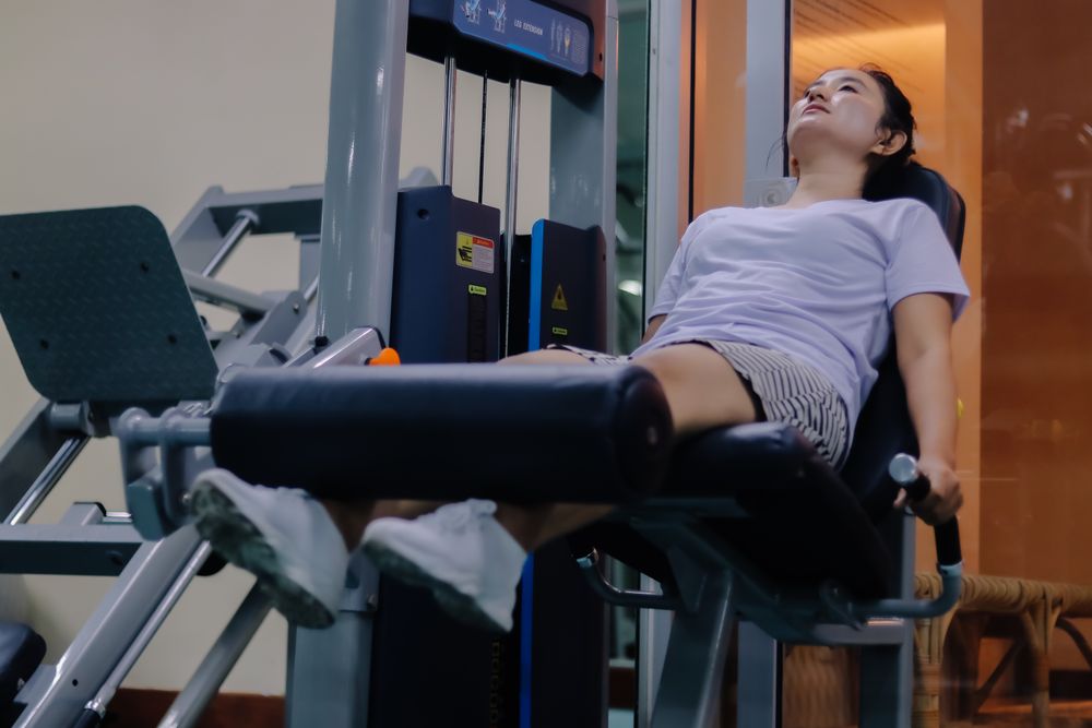woman using leg extension machine inside the gym.