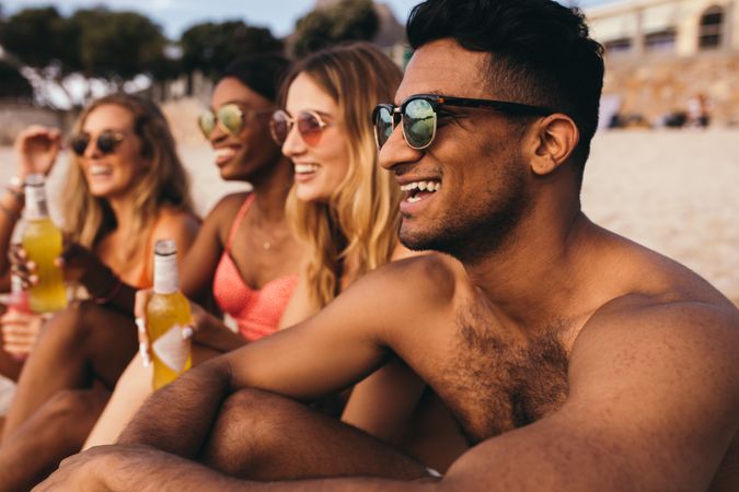 Close up of group of friends sitting at the beach wearing sunglasses