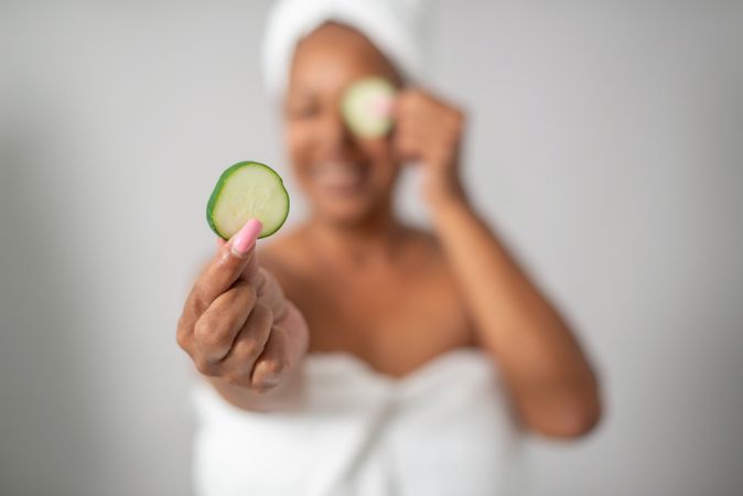 Woman showing cucumber slice during spa session