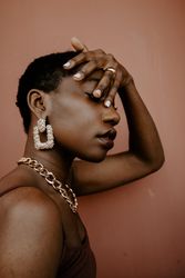 Side view of woman wearing gold necklace and gold ring and gold earring