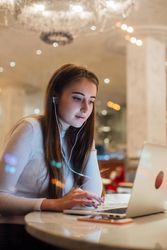 Woman in a restaurant working on her laptop with earbuds