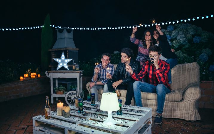 Happy friends holding sparklers at an outdoor party