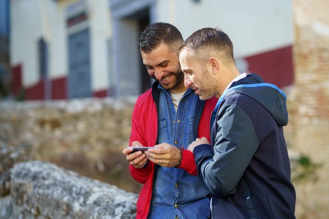 Two men smiling at something over a phone