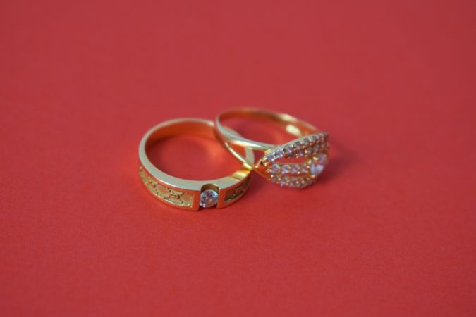 Two diamond gold wedding rings together on red background